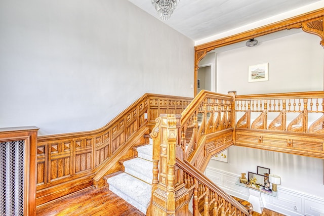 stairs featuring wood-type flooring and an inviting chandelier