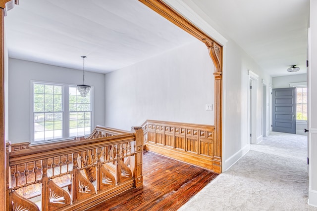 hallway featuring carpet flooring, an inviting chandelier, and a healthy amount of sunlight