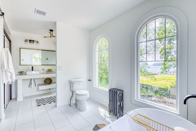 bathroom featuring radiator, a wealth of natural light, and tile patterned flooring