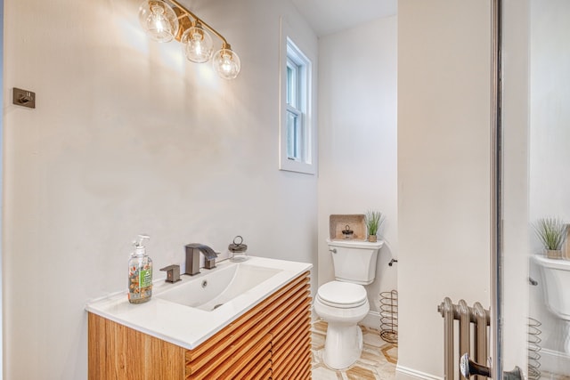 bathroom with radiator heating unit, vanity, and toilet