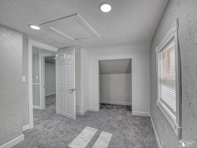 interior space with a textured ceiling and light carpet