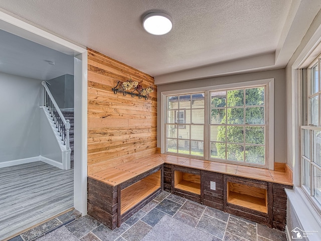 mudroom featuring a textured ceiling and wooden walls