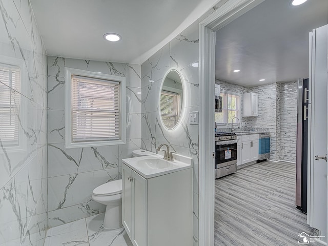 bathroom featuring vanity, toilet, and tile walls