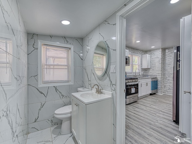 bathroom with wine cooler, vanity, tile walls, and toilet