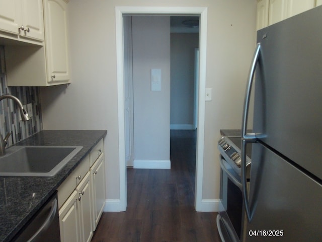 kitchen featuring baseboards, dark wood-style floors, white cabinetry, appliances with stainless steel finishes, and a sink