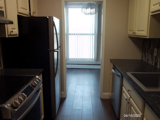 kitchen featuring a baseboard radiator, under cabinet range hood, a wealth of natural light, and stainless steel appliances