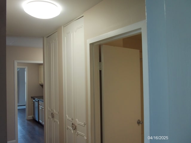 corridor featuring dark wood-style flooring, baseboards, and baseboard heating