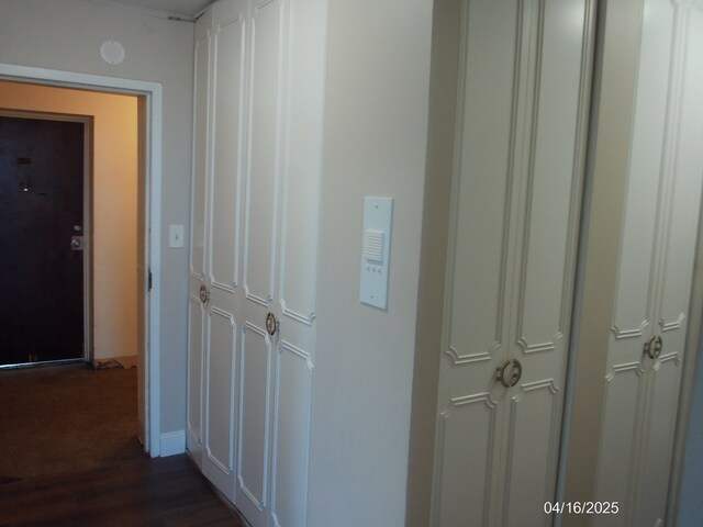 hallway with dark wood-style flooring and baseboards