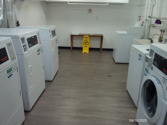 shared laundry area with a sink, washing machine and clothes dryer, and wood finished floors
