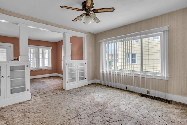 spare room featuring carpet, ceiling fan, and ornate columns