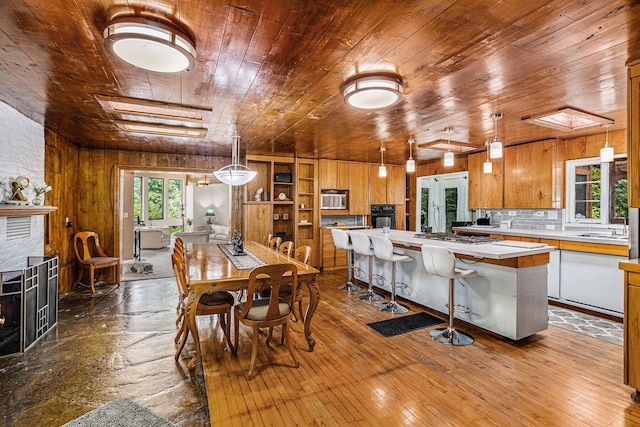6888 Ann Arbor Rd, Jackson, MI 49201 - dining space with wood ceiling, wood walls, a large fireplace, and dark wood finished floors