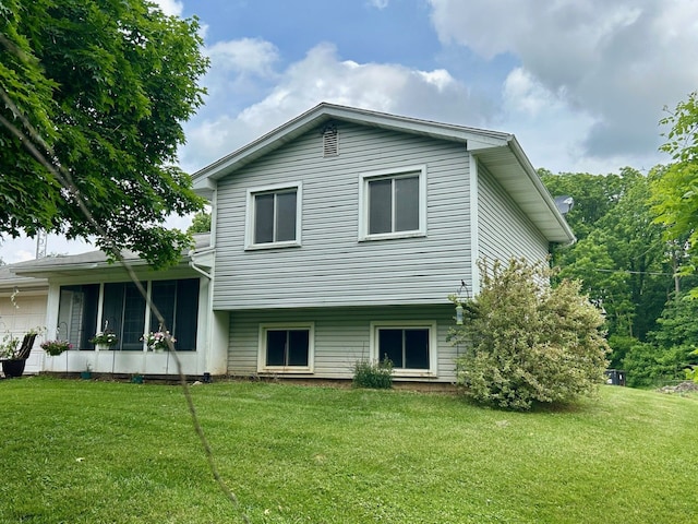 rear view of property featuring a lawn and a sunroom