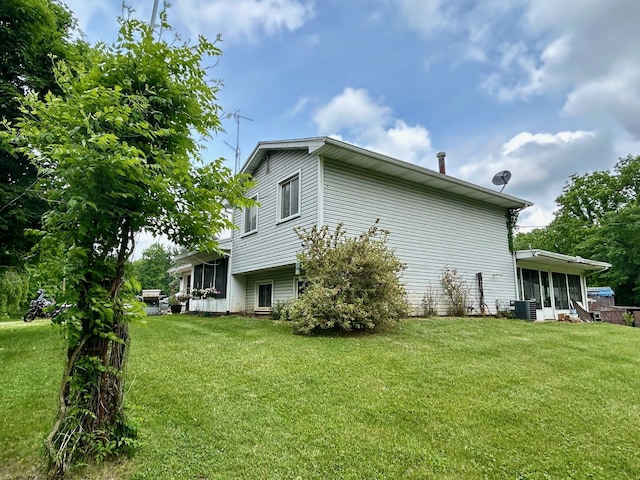 view of side of home with central AC, a lawn, and a sunroom