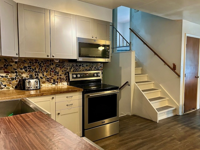 kitchen with butcher block counters, decorative backsplash, dark hardwood / wood-style flooring, and stainless steel appliances