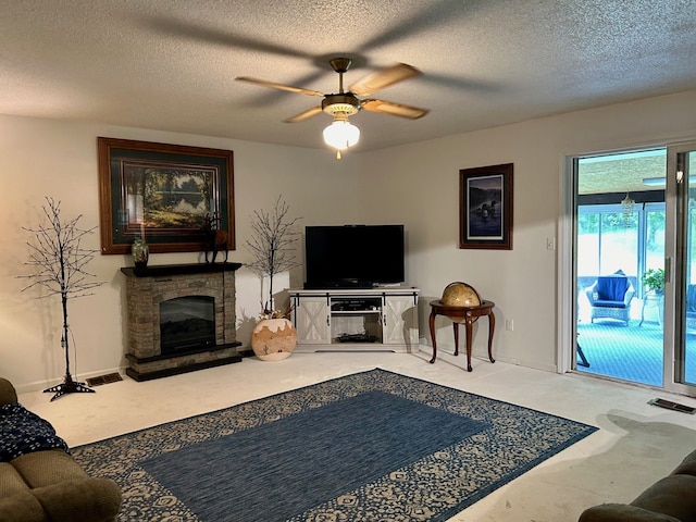 living room featuring a stone fireplace, ceiling fan, and a textured ceiling