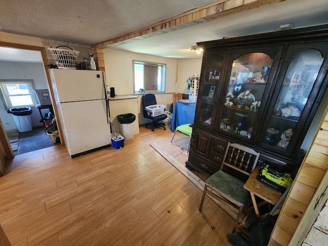 dining room with light wood-type flooring and a textured ceiling