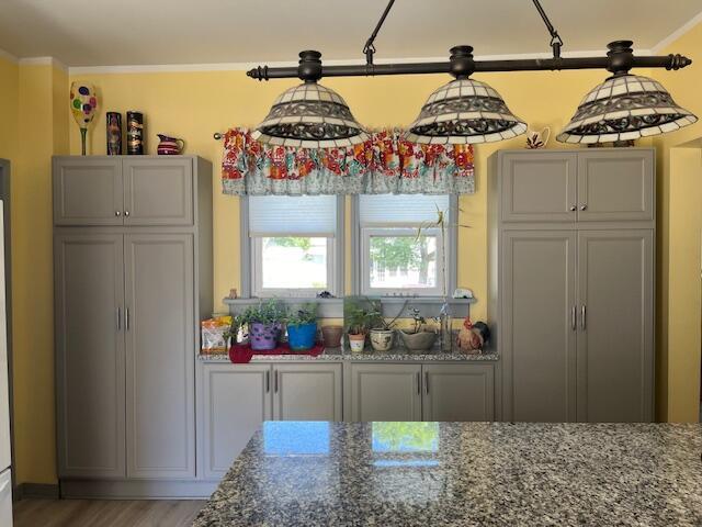 423 Oak St, Paw Paw, MI 49079 - kitchen featuring crown molding, dark stone counters, light wood-style floors, and gray cabinetry