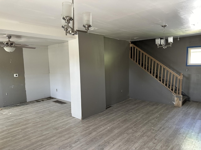 696 Highland Ave, Benton Harbor, MI 49022 - unfurnished living room featuring wood finished floors, stairs, a chandelier, and a ceiling fan