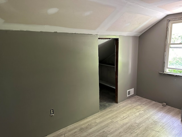 unfurnished room with hardwood / wood-style floors and vaulted ceiling