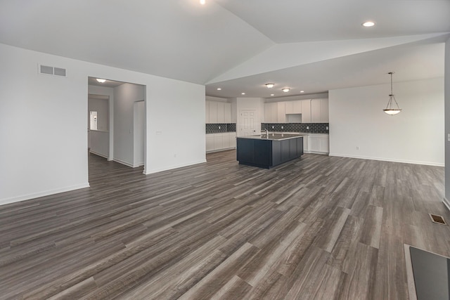 kitchen with lofted ceiling, hanging light fixtures, an island with sink, dark hardwood / wood-style flooring, and white cabinetry