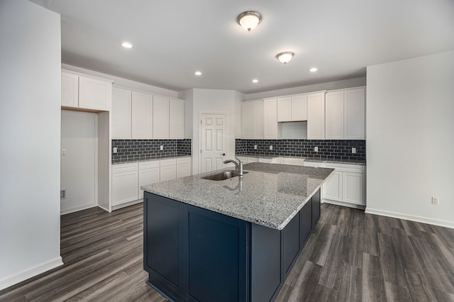 kitchen featuring dark hardwood / wood-style flooring, sink, white cabinets, and an island with sink