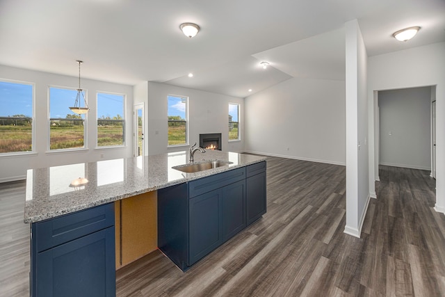 kitchen with blue cabinetry, light stone countertops, sink, dark hardwood / wood-style floors, and decorative light fixtures