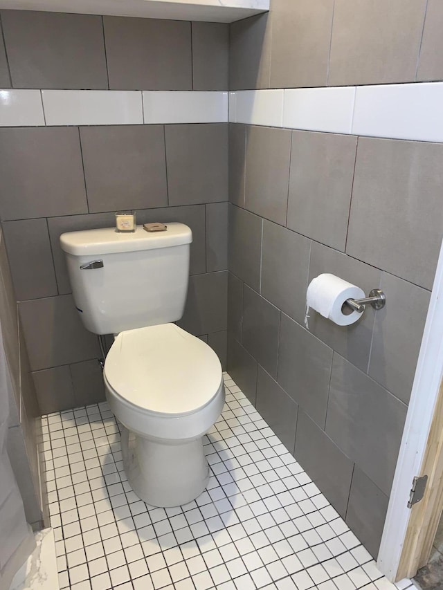 bathroom with toilet and tile walls