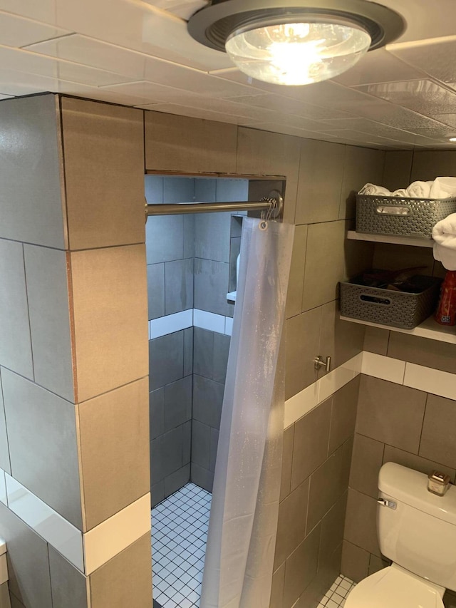 bathroom featuring walk in shower, toilet, and tile walls