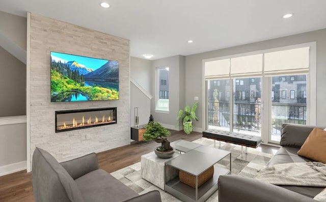 living room with a fireplace, light wood-type flooring, and a wealth of natural light