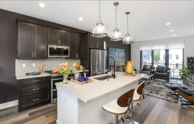 kitchen featuring hardwood / wood-style floors, appliances with stainless steel finishes, a kitchen island with sink, and sink