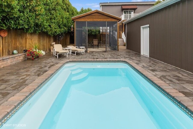 view of swimming pool with a patio and a sunroom