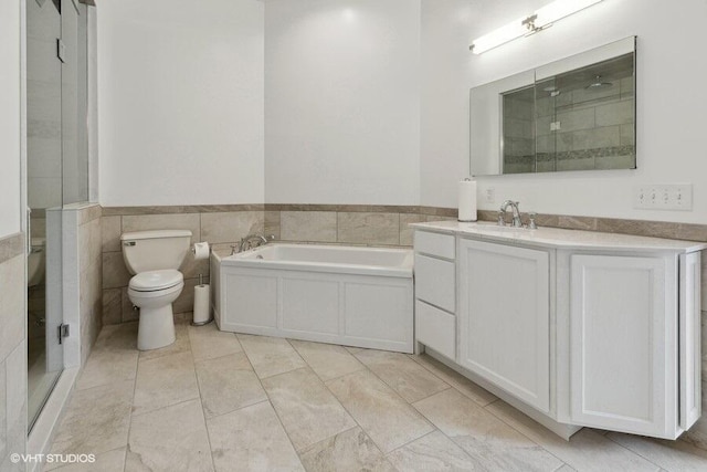 full bathroom featuring vanity, independent shower and bath, tile walls, and toilet