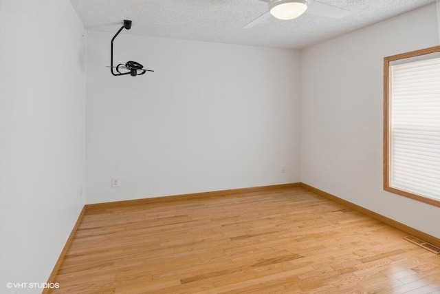 unfurnished room with a textured ceiling, light hardwood / wood-style floors, and ceiling fan