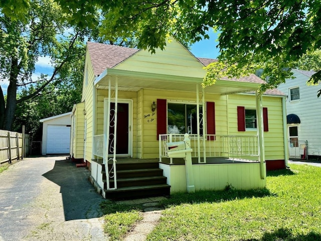 bungalow-style home with an outbuilding, covered porch, a front yard, and a garage