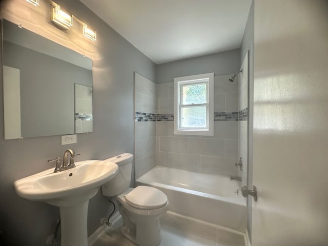 bathroom with tile patterned floors, tiled shower / bath combo, and toilet