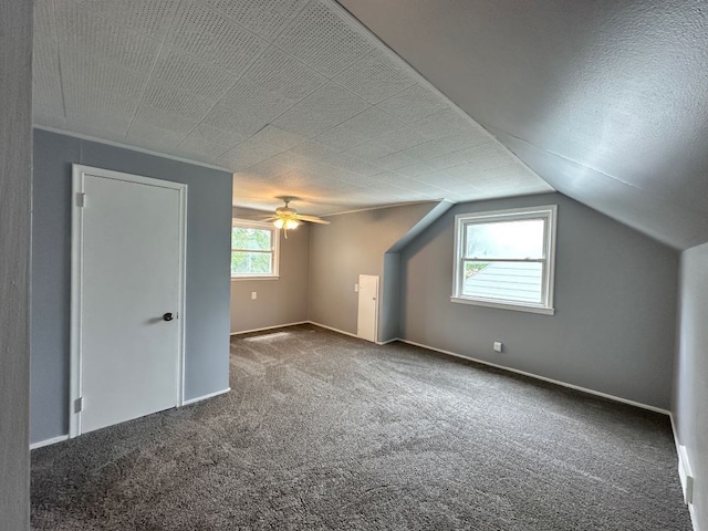 additional living space with a textured ceiling, ceiling fan, carpet, and vaulted ceiling