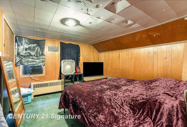 bedroom with carpet floors, radiator, cooling unit, and wood walls