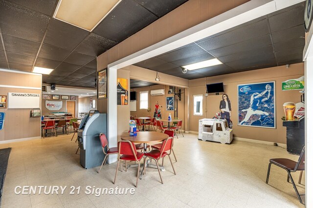 dining area with a paneled ceiling and a wall mounted air conditioner