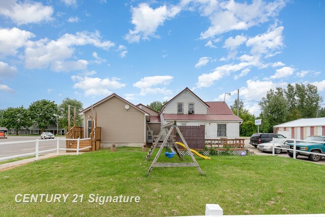 back of property featuring a lawn and a playground