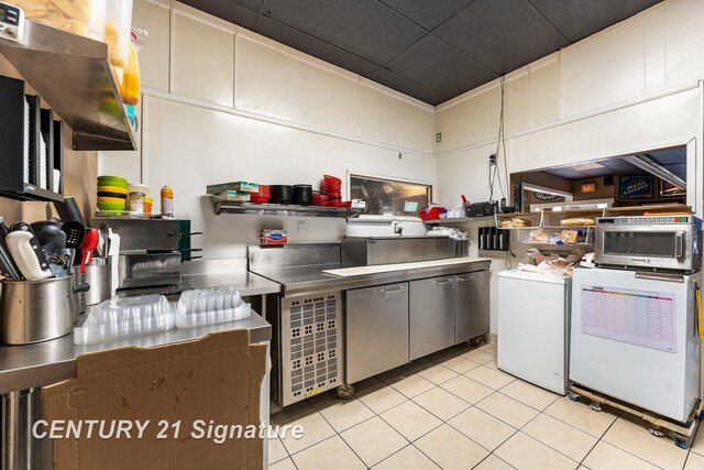 kitchen featuring washer / clothes dryer, stainless steel counters, and light tile patterned floors