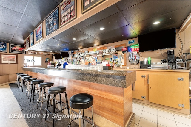 bar featuring light tile patterned floors and a paneled ceiling