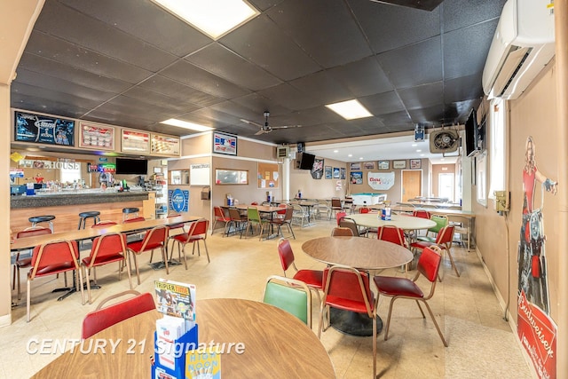 dining space with a paneled ceiling and a wall mounted AC