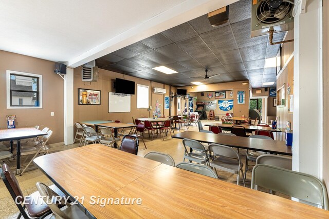 dining area featuring a paneled ceiling, a wealth of natural light, and an AC wall unit