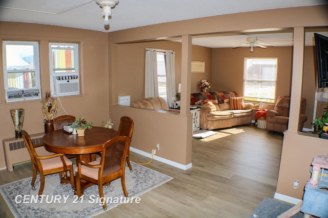 dining room with light hardwood / wood-style flooring, cooling unit, radiator heating unit, and plenty of natural light