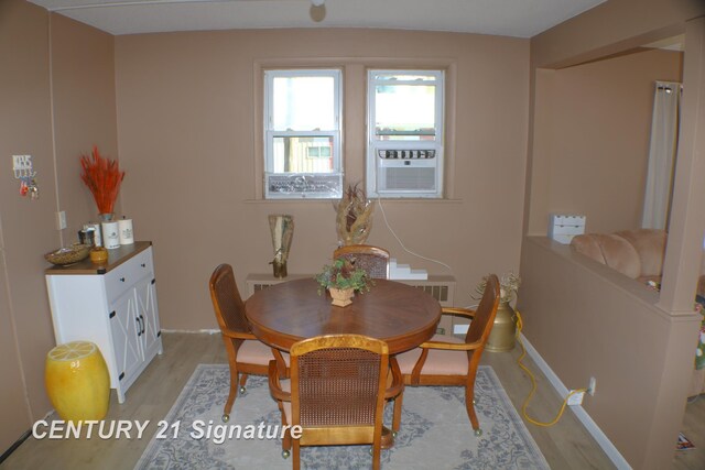 dining area with cooling unit and light hardwood / wood-style flooring