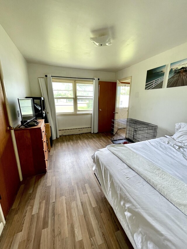 bedroom featuring baseboard heating and wood-type flooring