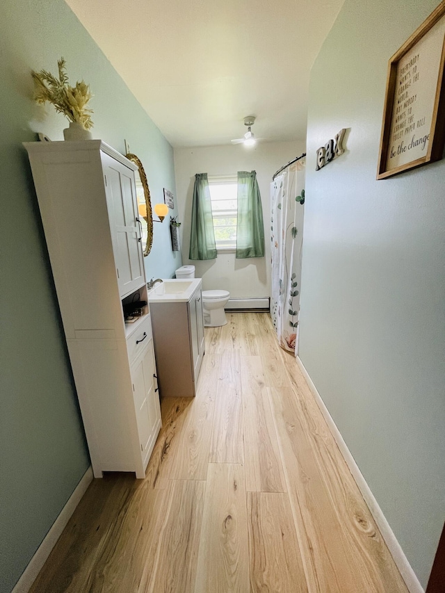 bathroom with hardwood / wood-style flooring, vanity, baseboard heating, toilet, and a shower with shower curtain