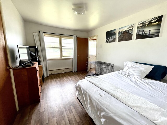 bedroom featuring baseboard heating and hardwood / wood-style floors