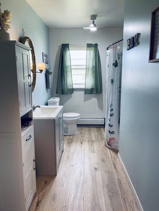 bathroom with a baseboard heating unit, vanity, wood-type flooring, curtained shower, and toilet