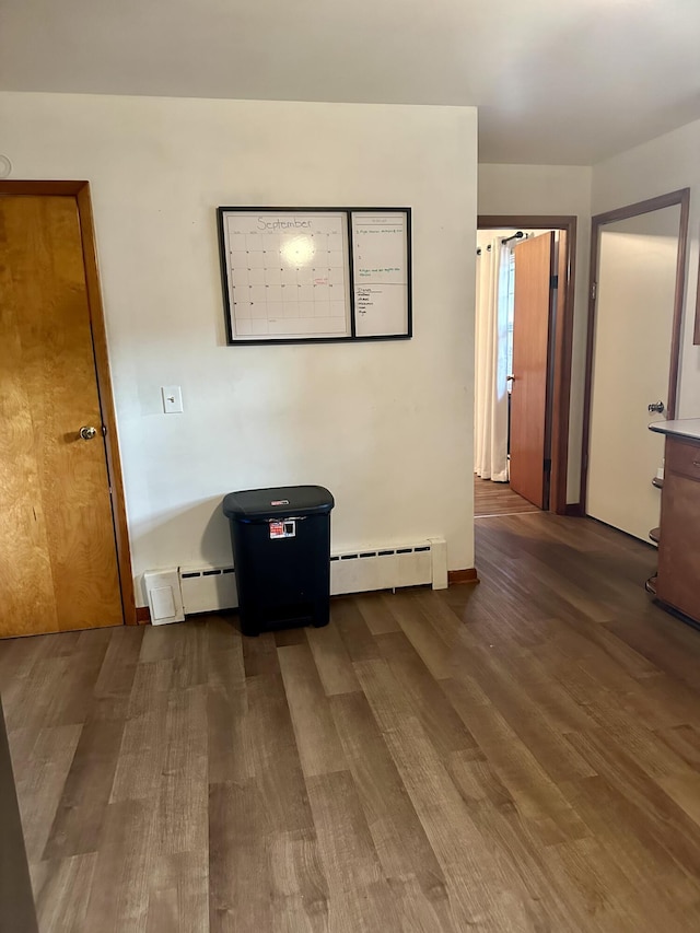 spare room featuring a baseboard radiator, dark hardwood / wood-style flooring, and a mail area